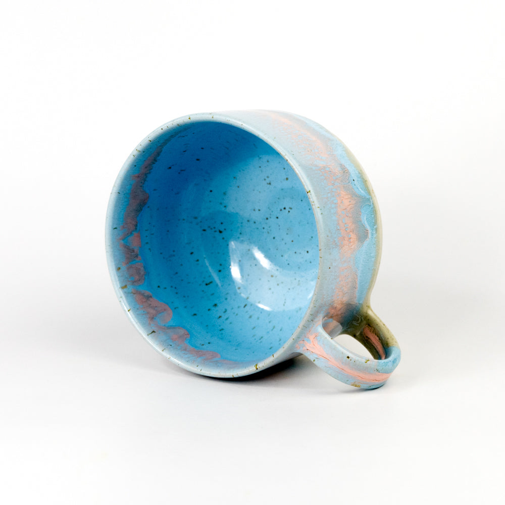 Ceramic mug with blue interior and speckled exterior on a white background