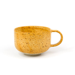 Yellow ceramic mug with speckled texture on a white background