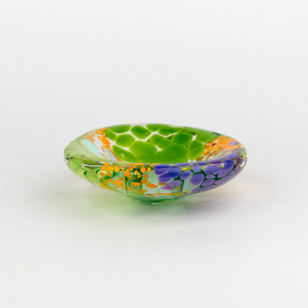 Decorative glass dish with green design on a white background