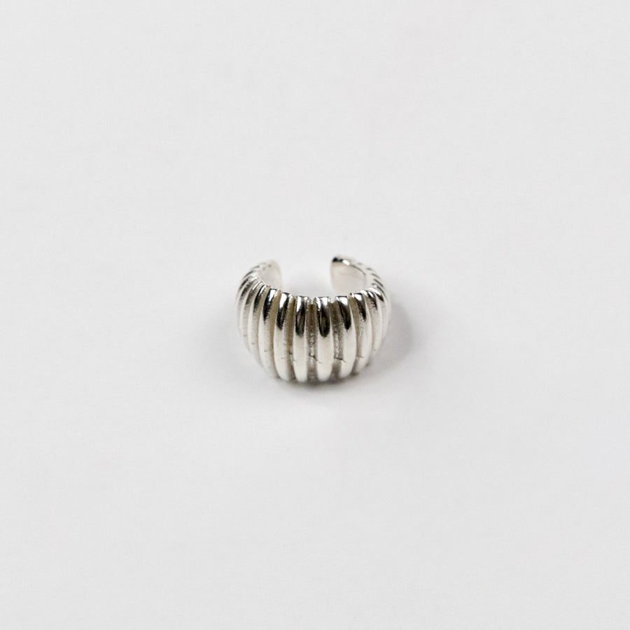 Silver ribbed ear cuff on a light gray background