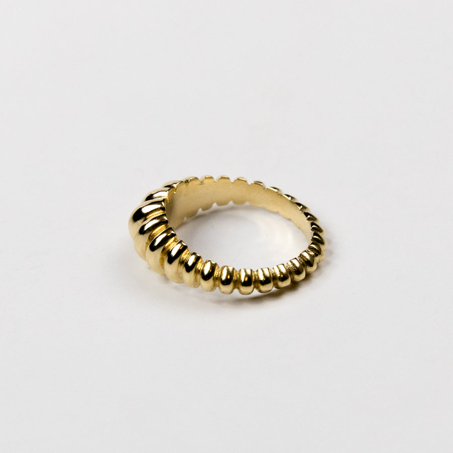 Gold ring with a ribbed design on a light gray background