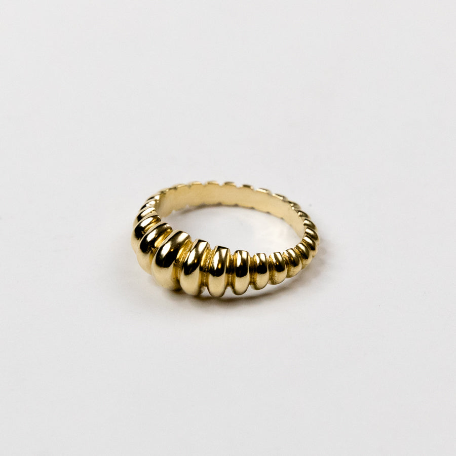 Gold ring with a ribbed design on a light gray background
