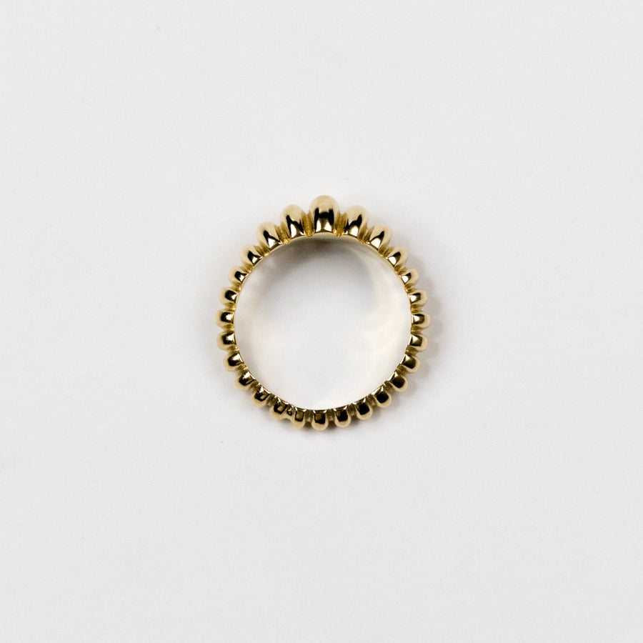 Gold ring with ribbed design on a light gray background