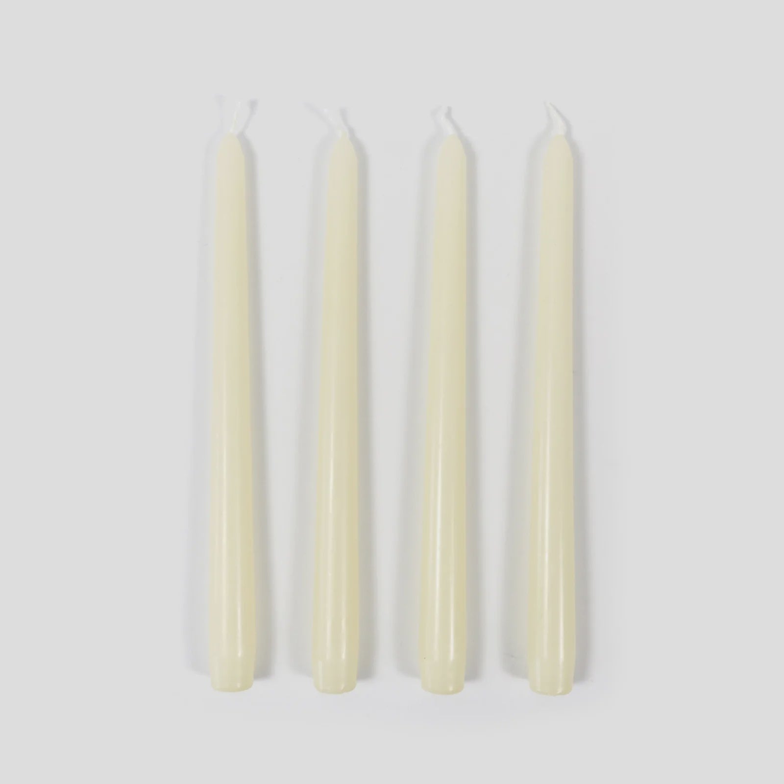Four white candles on a light gray background