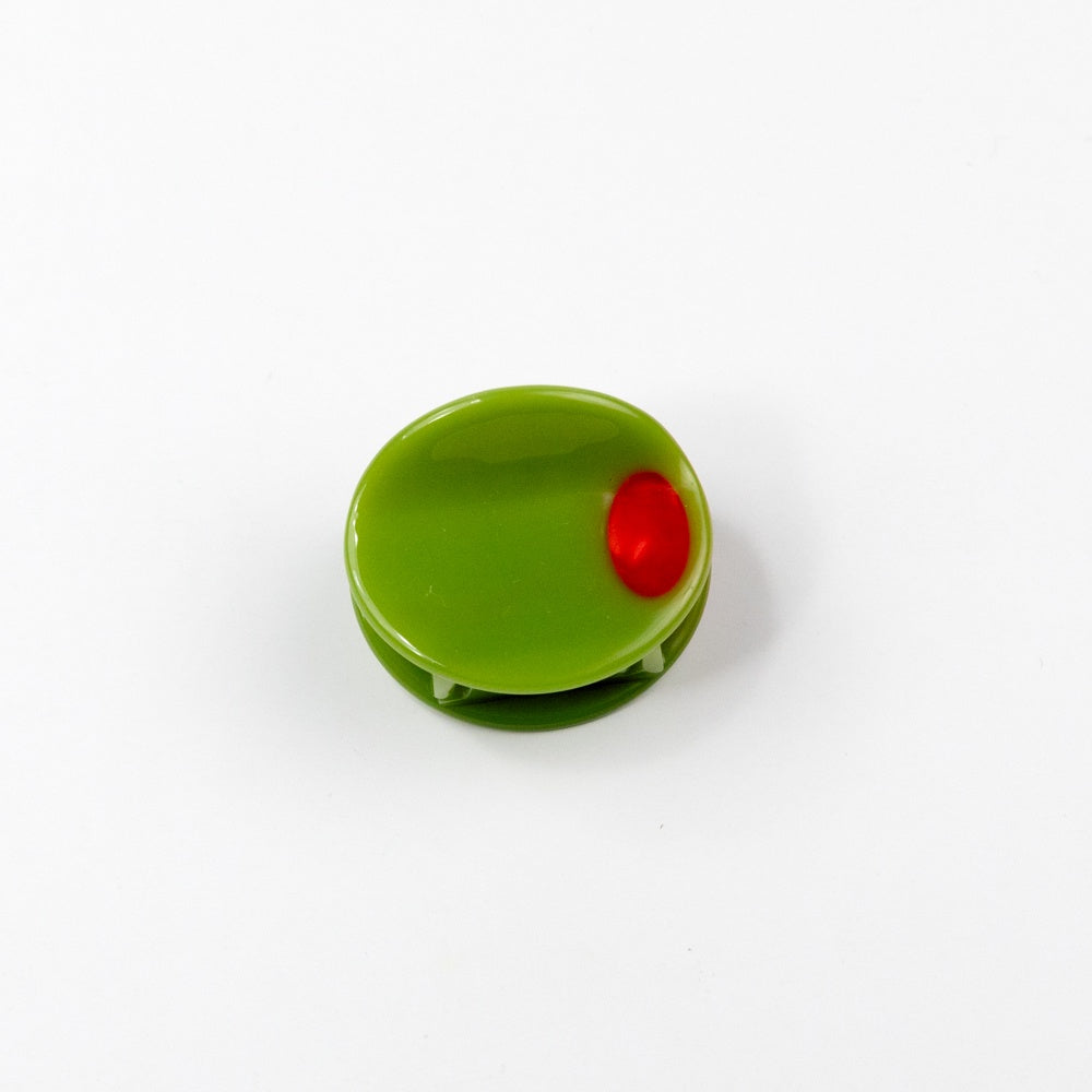 green olive with red pimento center shaped hair claw on a white background