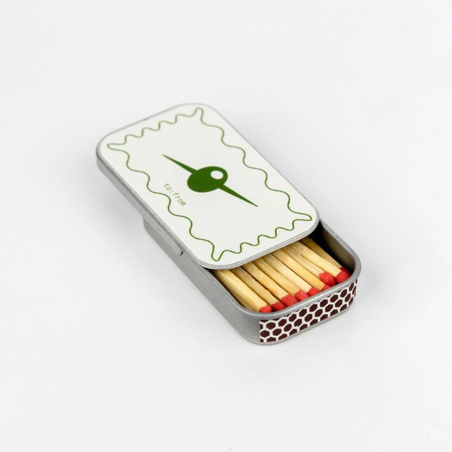 Matches in a tin with a green lid featuring an olive design on a white background