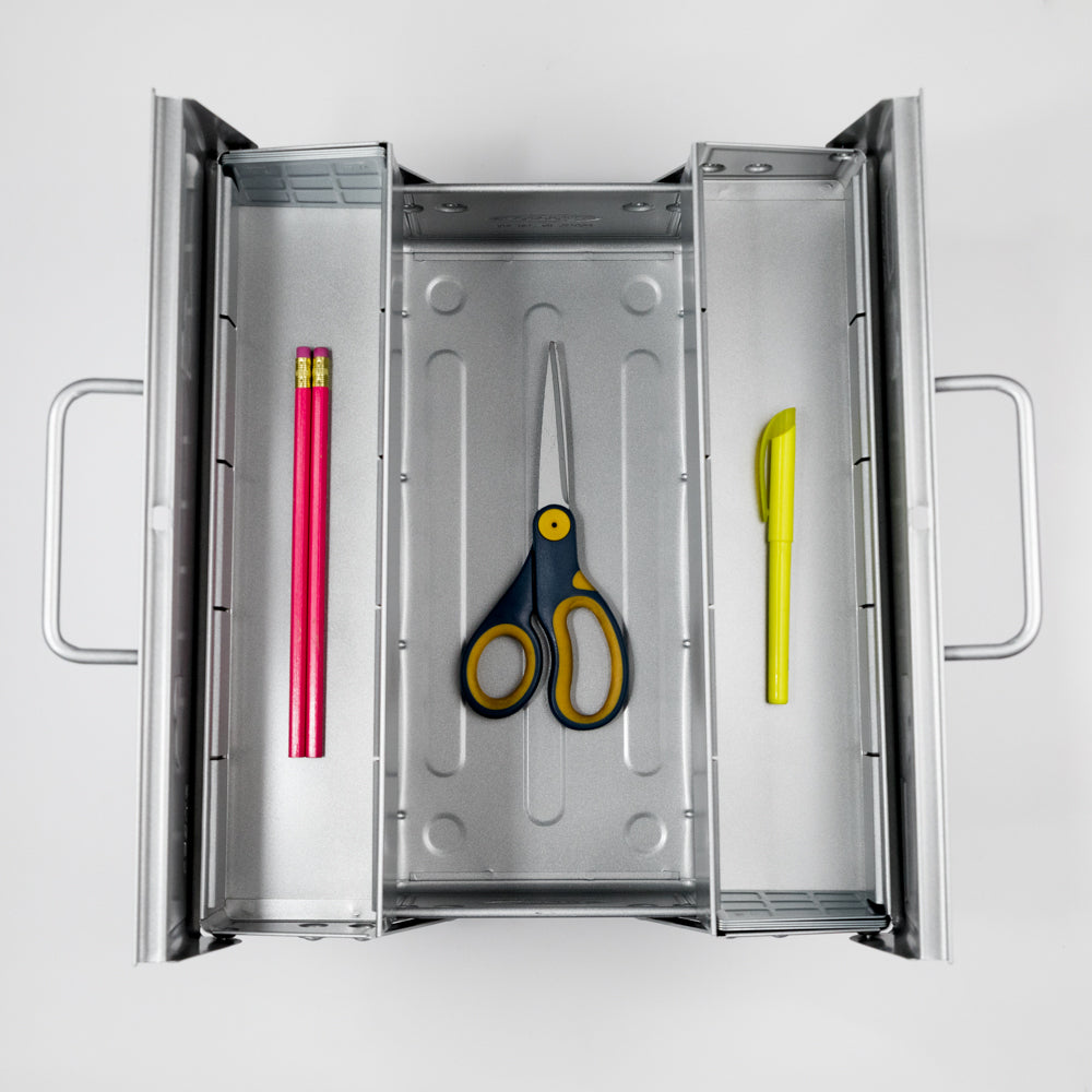 Metal tool box with a pink pencil, scissors, and yellow pen on a white background