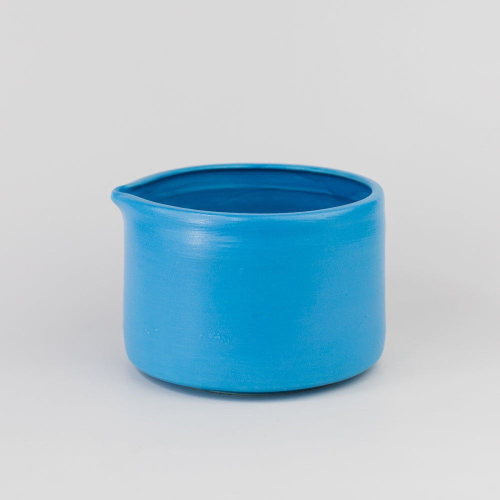 Blue ceramic pitcher on a light gray background