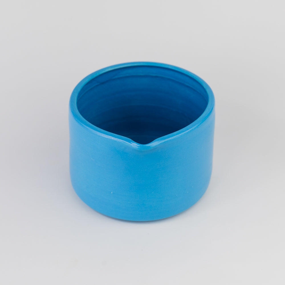 Blue ceramic pitcher on a light gray background