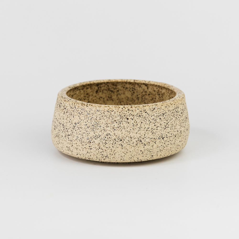 Speckled ceramic bowl on a light gray background