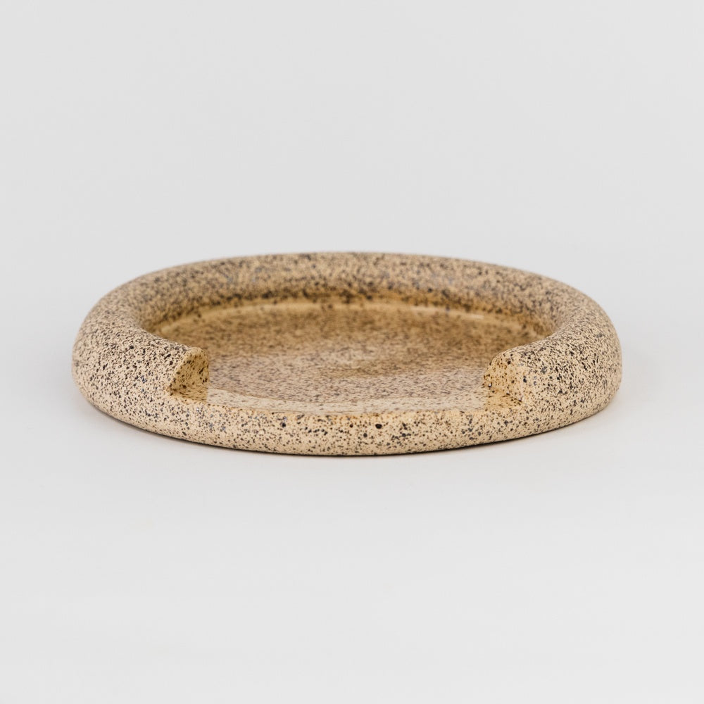 Round ceramic dish with textured surface on a light gray background