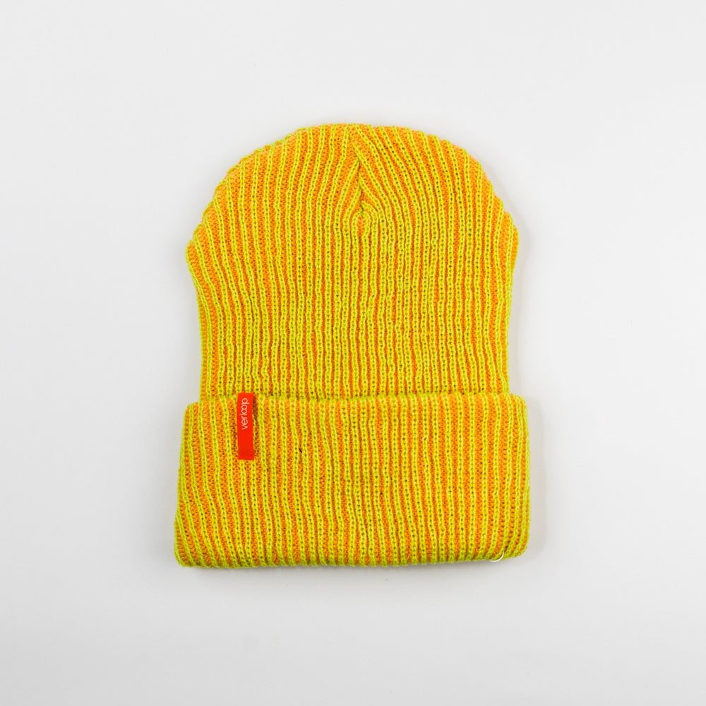 Yellow knit beanie with a red tag on a light gray background