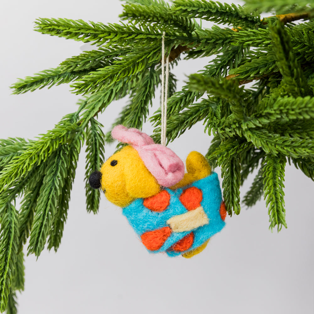 Felted dog ornament wrapped as a gift hanging on a Christmas tree branch.