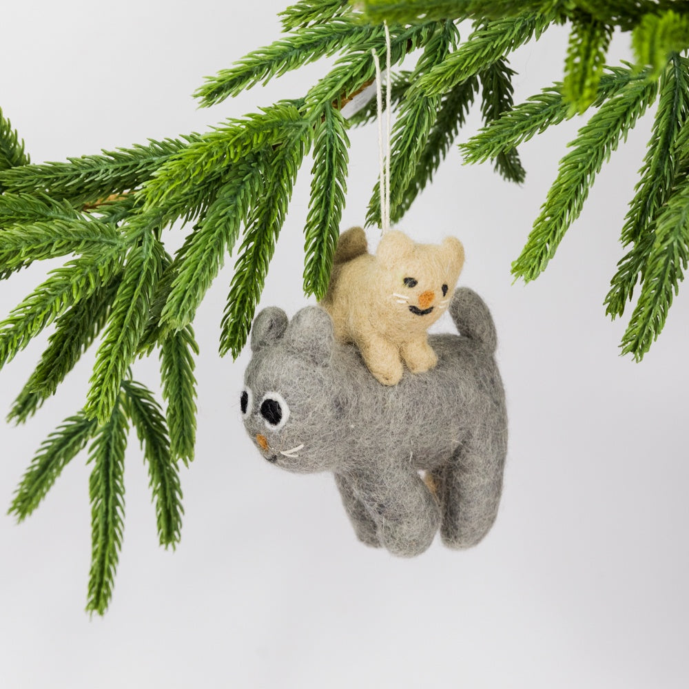 Felted cats ornament hanging from a Christmas tree branch.