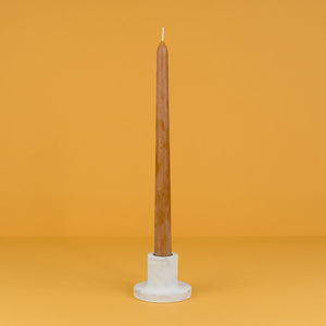 A concrete taper candle holder in white and light grey marble with terra cotta tapered candles 