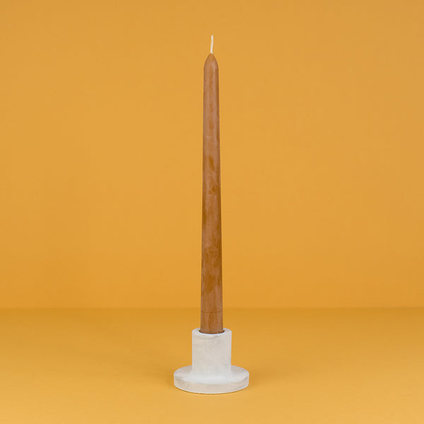 A concrete taper candle holder in white and light grey marble with terra cotta tapered candles 